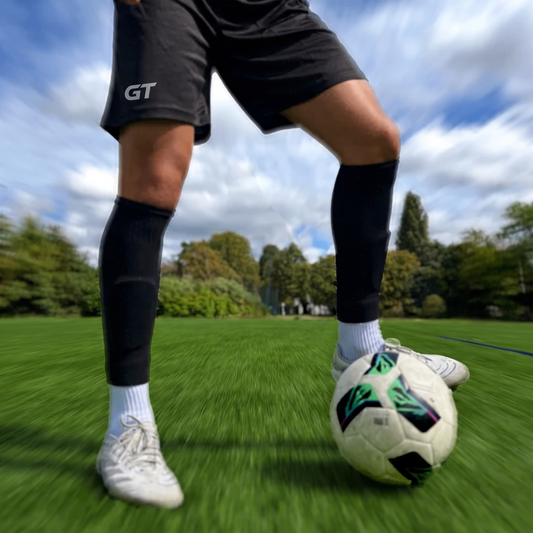 Voetballer met zwarte GT Pro Sleeve Socks over witte gripsokken op het voetbalveld | GT Sport Selection